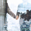 Two businesspeople shaking hands with a city skyline overlay